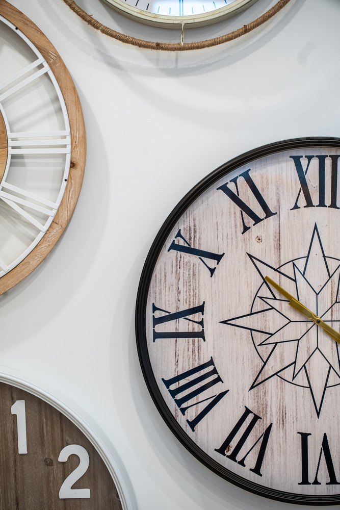 A cluster of wall clocks overlapping on a white wall