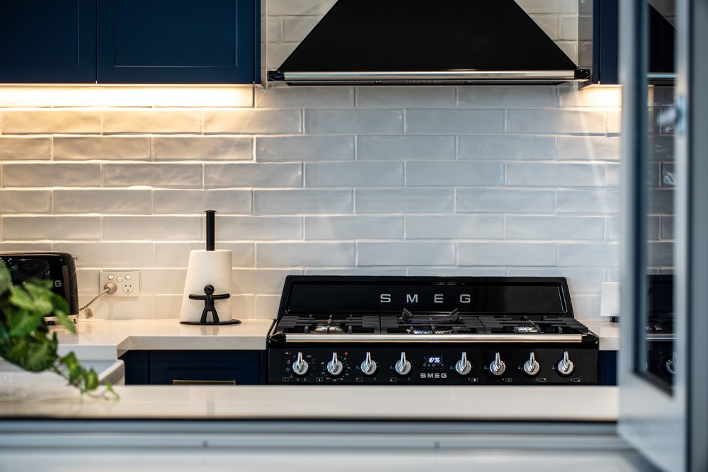 A black range cooker under warm cabinet light, seen through an open window