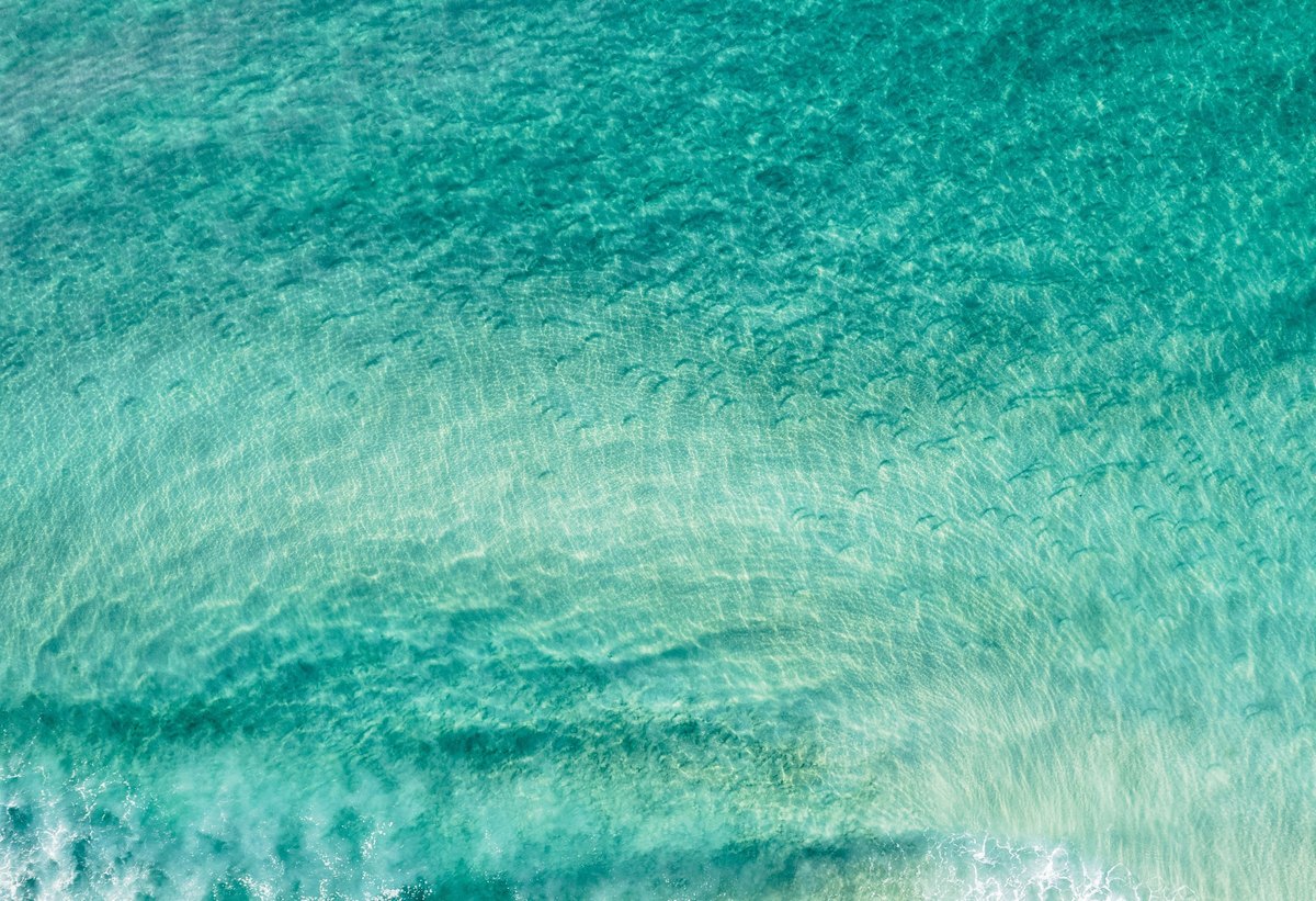 Drift — Aerial view of clear turquoise water rippling over sand