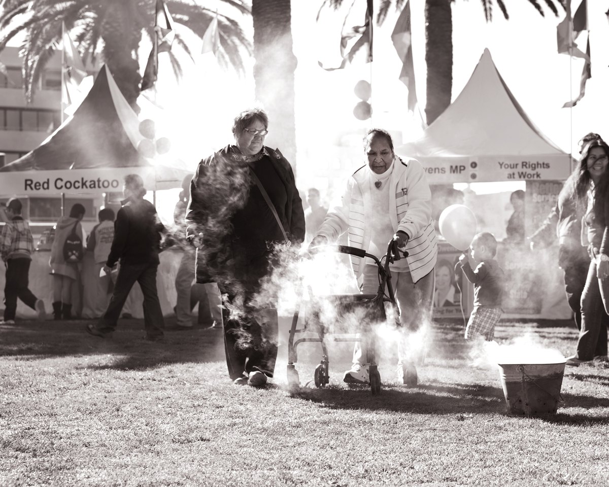 Through — Black-and-white photograph of people walking through smoke at an outdoor gathering